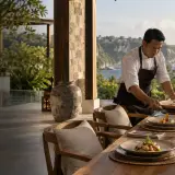 Private chef setting a candlelit dinner on a clifftop terrace at a Bukit Peninsula villa