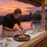 Private chef plating a fine dining course at a luxury Seminyak villa pool at sunset