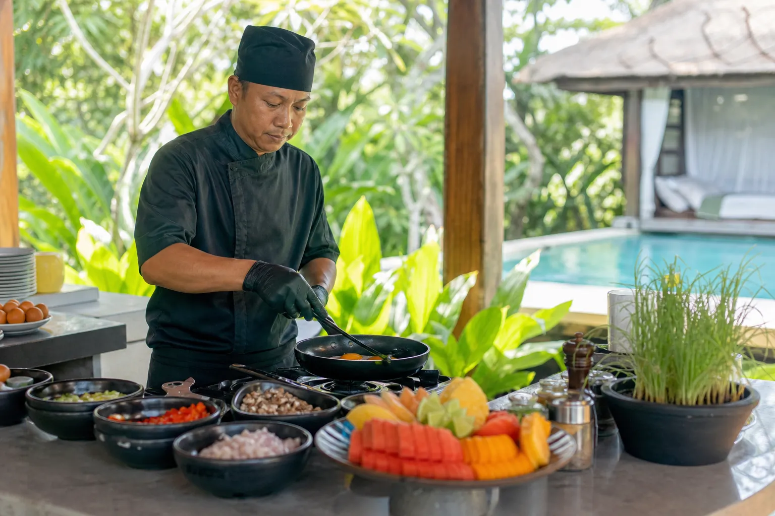 Breakfast chef preparing eggs and tropical fruit in a Bali villa kitchen