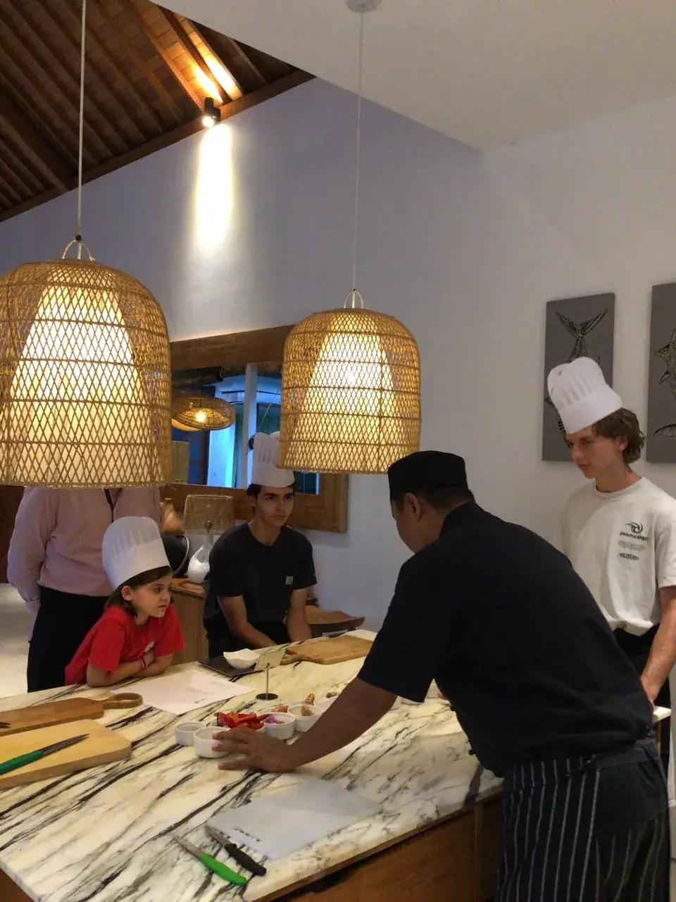 Chef teaching a family at a marble villa kitchen island during a private cooking class Bali