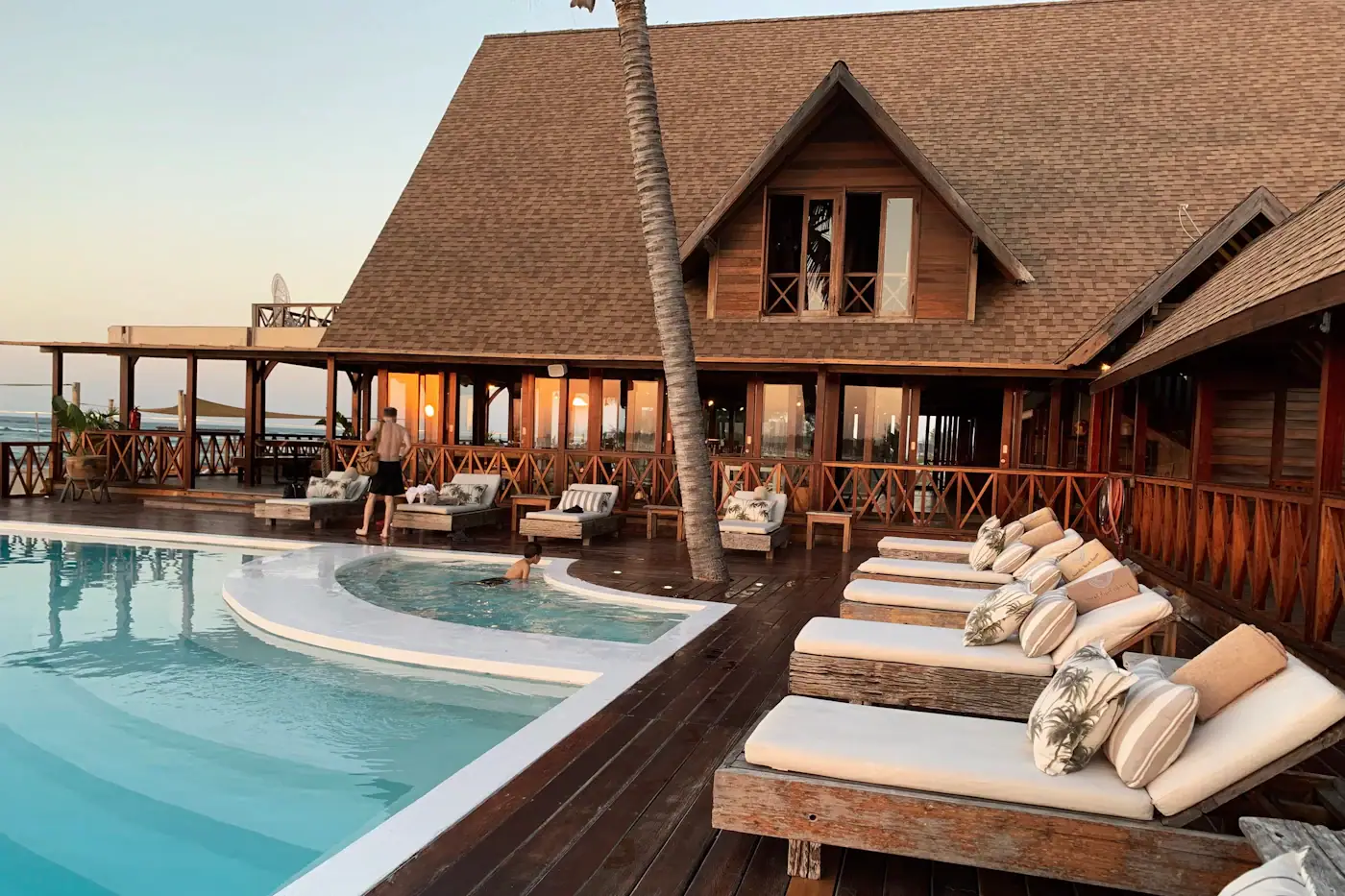 Resort swimming pool with sun loungers beside a timber pavilion
