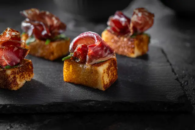 Toasted brioche bites topped with cured ham, a myCHEF canapé