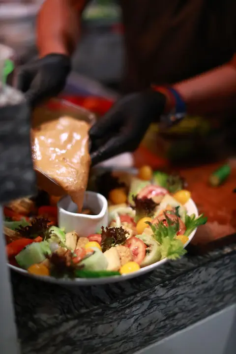 myCHEF chef finishing a colourful platter with sauce