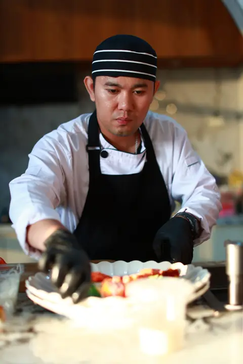 myCHEF chef in a black apron plating a fresh sashimi platter in a villa kitchen